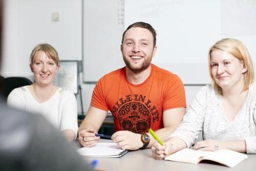 people discussing at a table whilst taking notes