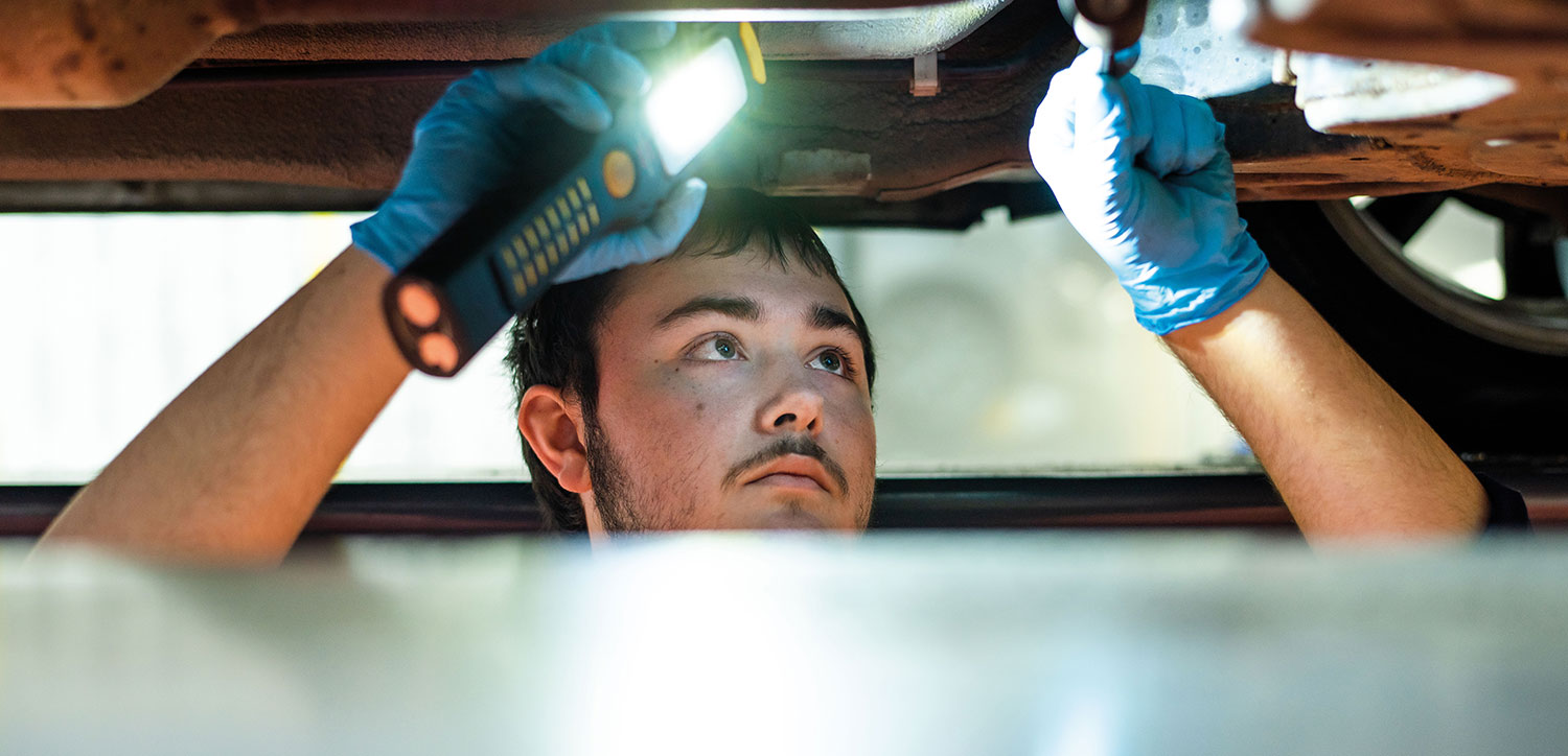 Student inspecting underside of car